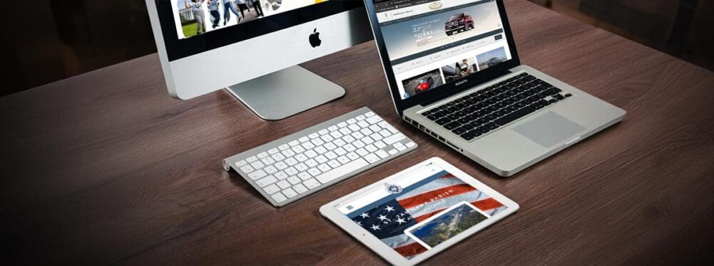 An iMac, Macbook Pro, and Ipad on a dark wood desk with stpao.org, lamarquelincoln.com, and gricua.net on each display