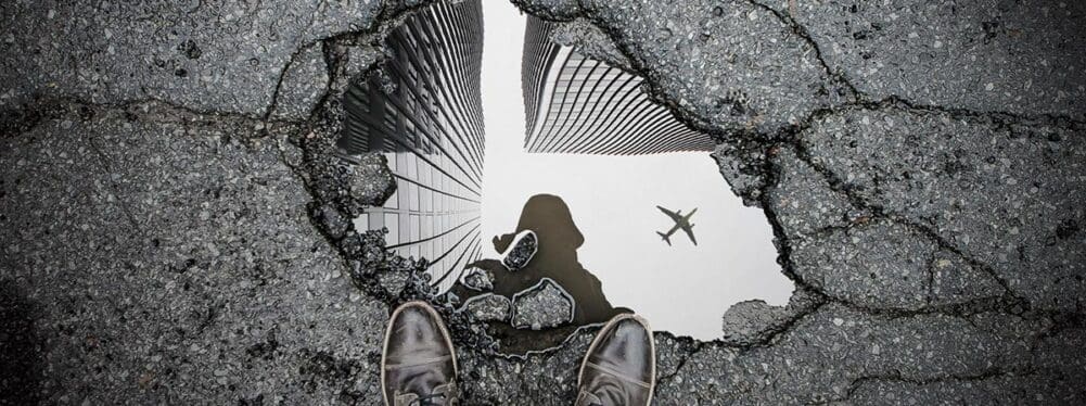 birdseye view of a pothole with water in it and reflecting downtown
